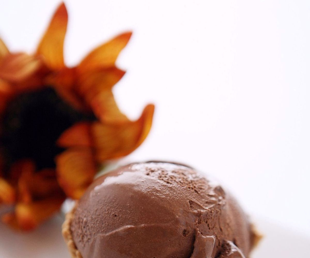 Hands scooping creamy gelato into a cone